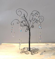 a wire tree with beads hanging from it's branches on top of a wooden table