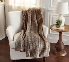 a white chair with a brown blanket on it