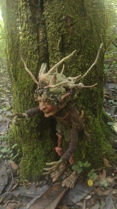 a mossy tree with an odd looking head and antlers on it's face