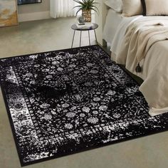 a black and white rug in a bedroom with a plant on the side of the bed