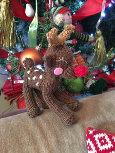 two knitted reindeers sitting on top of a couch next to a christmas tree