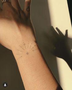 a person's arm with a small tattoo on it and the sun in the background