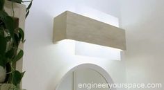 a bathroom with a round mirror and light fixture above the sink in front of a white wall