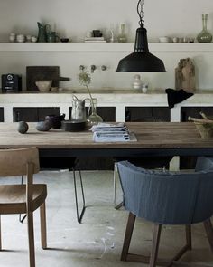 a dining room table with chairs and shelves in the background