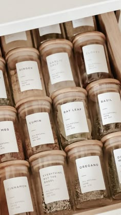 many jars filled with different types of spices on display in a wooden box next to each other