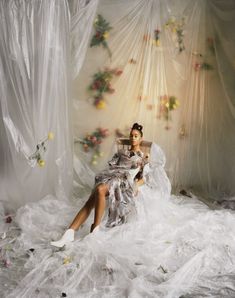 a woman is sitting in a chair covered with plastic wrap and flowers on the wall