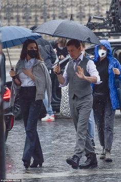 people walking in the rain with umbrellas and masks covering their faces from the rain