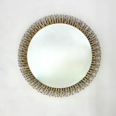 a round mirror on the wall with gold and silver trimmings around it's edge