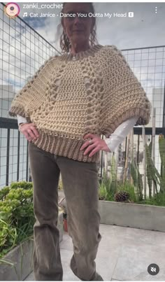 the woman is wearing a crocheted ponchy with her hands on her hips