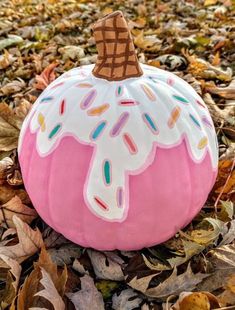 a painted pumpkin with sprinkles and ice cream on it sitting in leaves