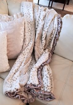 a white couch with two pillows on it and a blanket draped over the back of the couch