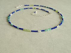 This multi gemstone blue lapis necklace has an array of gorgeous small gemstones -- small blue lapis lazuli, rare Ethiopian teal opals, green peridot, teal apatite, and Sleeping Beauty turquoise, with a variety of sterling silver beads. This slender blue lapis multi gemstone necklace closes with a sterling silver lobster clasp, and has a small lapis charm at the closure. The small natural gemstones in this necklace are so beautiful together, and come in many shapes and sizes. The blue lapis is r Sterling Silver Blue Jewelry With Tiny Beads, Blue Sterling Silver Jewelry With Tiny Beads, Blue Sterling Silver Necklaces With Tiny Beads, Blue-green Round Beads Jewelry For Gifts, Blue-green Round Beads Jewelry Gift, Dainty Blue Necklace With Natural Stones, Multi Gemstone Necklace, Lapis Necklace, Blue Lapis Lazuli