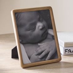 a wooden frame with a baby's hand resting on it next to a book