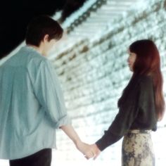 two people holding hands while standing in front of snow covered steps on a snowy day