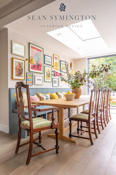 a dining room table with chairs and pictures on the wall above it, along with other furniture