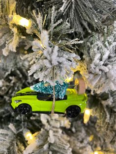 a green car with a christmas tree on it is in the middle of a white and silver christmas tree