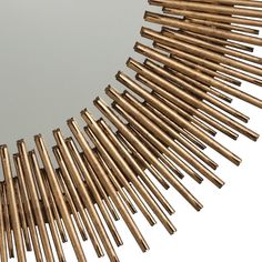 a mirror that has some gold sticks in the shape of a sunburst on it