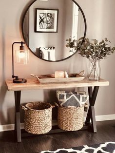 a wooden table with baskets under a round mirror on the wall next to a black and white rug