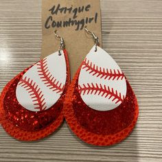 a pair of red and white glittered earrings with baseball stitching on the side