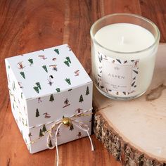 a candle sitting next to a white box on a wooden table near a piece of wood