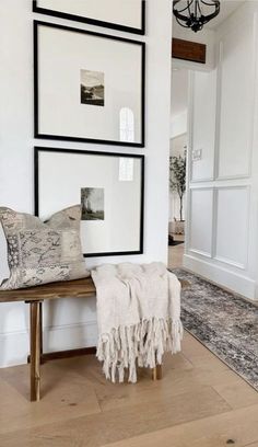 a white room with pictures on the wall and a wooden bench in front of it