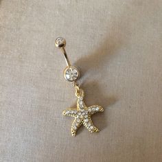 Gold Starfish Belly Button Ring - gold belly ring, crystal belly ring, beach lover gift Pretty belly ring in surgical steel colored GOLD with a double gem in clear and a rhinestone encrusted starfish with embossed detal (shown in hand in silver)   entire piece approx 1 5/8" long. /42mm 14 gauge Large barbell rhinestone approx 7mm across - star pendant Approx 7/8 (24mm) long  Comes in an organza gift bag matching necklace available To keep the rhinestones looking their best I recommend you do not wear this piece while swimming or bathing. NOT RECOMMENDED FOR THOSE WITH SENSITIVE SKIN, METAL ALLERGIES, OR NEW PIERCINGS also in silver https://www.etsy.com/listing/194426643/belly-button-ringstarfish-bellybutton?ref=shop_home_active_3 I DO NOT OFFER RETURNS or EXCHANGES, so please select carefu Starfish Belly Button Piercing, Cute Gold Belly Button Piercing, Gold Navel Jewelry, Gold Belly Button Jewelry, Belly Button Jewellery, Beachy Belly Button Piercing, Star Belly Button Piercing, Summer Belly Button Rings, Belly Button Piercing Gold