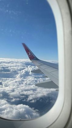 the wing of an airplane flying above clouds and blue sky with a white circle on it