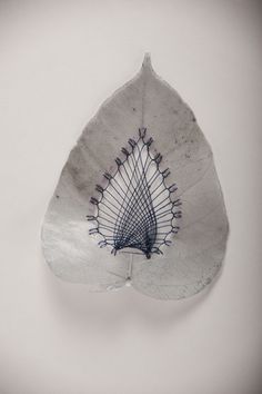 a white and blue leaf shaped object is hanging on the wall, with lines drawn across it