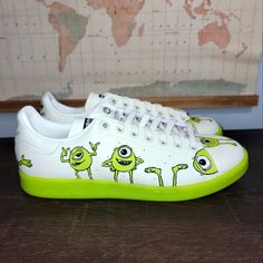 a pair of white and green sneakers with monsters painted on the upper part of them