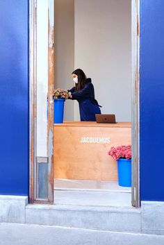 a woman wearing a face mask sitting at a desk in front of a blue wall