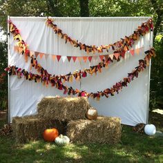 hay bales and pumpkins are arranged in front of a white backdrop with bunting