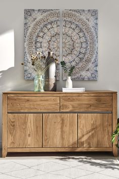 a wooden dresser with two vases on top of it next to a large painting