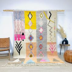 a multicolored rug is displayed on the floor next to a chair and table