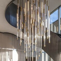 a large chandelier hanging from the ceiling in a room with stairs and windows