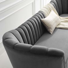 a large gray couch sitting in front of a white wall with pillows on top of it