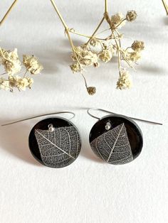 a pair of earrings sitting on top of a table next to dried flowers and branches