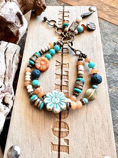 Just love how this double strand boho nature bracelet turned out! Large alabaster daisy with a metallic green blue wash, orange aventurine carved flower, abalone shell and other colors accented with bronze metals. Quality gift idea or something special for yourself! If there are ANY issues with my artistry or product, I will honor my work Details:  Large alabaster metalic green blue daisy czech bead 18mm Orange aventurine carved flower and saucers Abalone shell rondelles 6mm Lava rock dark teal 8mm White magnesite seed beads Turquoise faceted rondelle glass beads 5mm Turquoise thin czech glass 6mm Various glass beads and gemstones on danglies Tiny glossy bronze seed beads Brass stamped mountain trees small charm Brass leaf charm Bronze metal beads, spacers, chain and components  Bronze met Hippie Green Bracelet Jewelry, Adjustable Turquoise Nature-inspired Jewelry, Adjustable Blue Earthy Jewelry, Rustic Adjustable Jewelry With Natural Stones, Earthy Blue Jewelry For Festivals, Earthy Turquoise Bracelet Jewelry, Bohemian Turquoise Amazonite Jewelry, Adjustable Turquoise Bracelets With Nature-inspired Style, Blue Double Strand Bohemian Bracelets