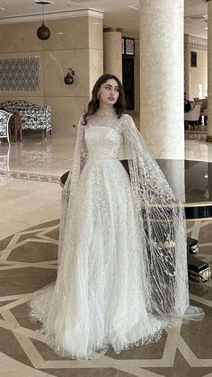 a woman in a white wedding dress standing next to a chair