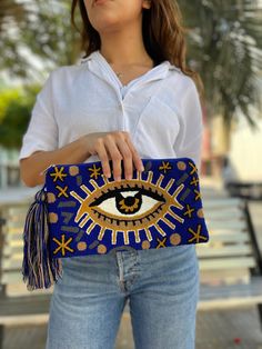 "Our cute Evil Eye Wayuu Clutch Bags are the Perfect addition to your Summer/Fall  wardrobe in Boho Chic Style. Stand out wearing a fashionable Clutch on your Shoulder , Crossbody or as a handbag by Removing the Strap!  Lightweight, durable (Sturdy ) and machine washable, this stunning Clutch is the perfect accessory for every day, a getaway, or poolside/beach day! Details: Removable Strap that can be used on any bag as Well  Hand-crocheted using double thread crochet and one needle technique inside lining Material: Made from acrylic threads (Cotton + Polyester) Overall dimensions (approximate): Clutch : 11.7\" Wide x 6.7\"H Strap: 19\" Drop (nestle your Strap on your shoulder or cross) , full length 100cm (39 inches) Hand-crocheted by talented Wayuu women in La Guajira Peninsula, in north Blue Embroidered Clutch Shoulder Bag, Blue Embroidered Vacation Bag, Blue Rectangular Clutch For Vacation, Trendy Blue Pouch Clutch, Trendy Blue Clutch For Everyday Use, Trendy Blue Everyday Clutch, Blue Pouch Clutch For Beach, Trendy Handmade Blue Bags, Blue Embroidered Bags For Beach