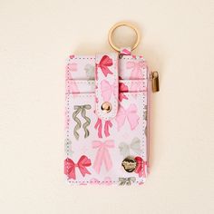 a small pink wallet with a gold keychain hanging from it's side