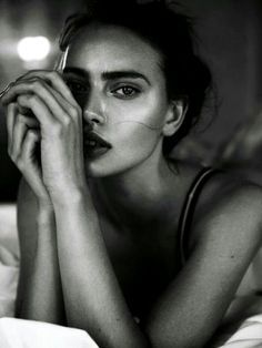 a black and white photo of a woman laying in bed with her hand on her face