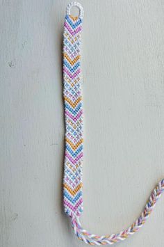 a white and blue bracelet with multicolored beads hanging from it's side