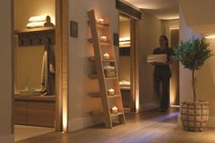 a woman standing next to a ladder in a room with candles on the floor and shelves