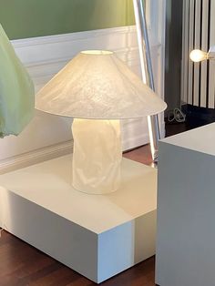 a lamp sitting on top of a white table next to a wall mounted radiator