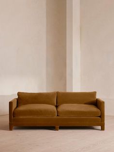 a brown couch sitting on top of a hard wood floor next to a white wall