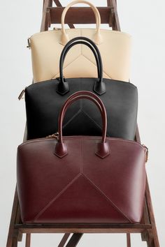 Luxurious and versatile, the Victoria Bag in rich Burgundy has a structured body for protected storage and offers the flexibility of both top handles and an adjustable and removable strap. Design details include an engraved zip puller and padlock closure, a snap button to hold the zip tape in place and a removable leather debossed charm. Visual interest is added with leather panels stitched in the shape of the house’s signature V design, while textile lining adds a sumptuous finishing touch. Vic Luxury Burgundy Bags For Everyday Use, Modern Burgundy Satchel With Detachable Handle, Luxury Burgundy Bag For Everyday, Luxury Burgundy Tote Satchel, Classic Business Bags With Round Handle, Classic Burgundy Bag With Detachable Handle, Saffiano Leather Satchel With Handles, Burgundy Top Handle Satchel For Business, Saffiano Leather Satchel Bag With Handles