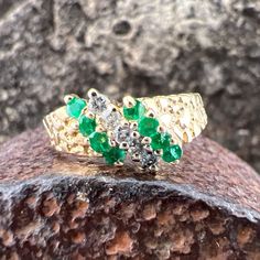 Gorgeous Emeralds accented by Diamonds and set in a 14k Yellow Gold Ring. US Size 6 1/2 Emeralds 0.32 ctw, approximately  Diamonds 0.1 ctw, approximately  Widest point measures approximately 7.5 mm Tapers down to approximately 1.9mm at the back of the shank Weighs approximately 2.8 grams. Stamped 14K Classic Green Multi-stone Diamond Ring, 14k Gold Cluster Diamond Ring Fine Jewelry, Green Diamond Cut Diamond Ring, Dazzling Yellow Gold Multi-stone Diamond Ring, Green Multi-stone Diamond Ring, White Gold Cluster Diamond Ring With Multi-stone, Heirloom Multi-stone Round Cut Diamond Ring, Emerald Cluster Ring With Brilliant Cut Diamonds, Diamond Multi-stone Jewelry For May Birthstone