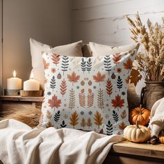 a pillow with leaves on it next to candles and pumpkins