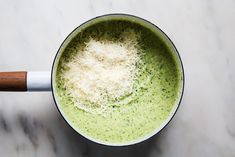 a cup filled with broccoli and cheese on top of a marble countertop