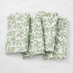 four green and white napkins sitting on top of a counter next to each other